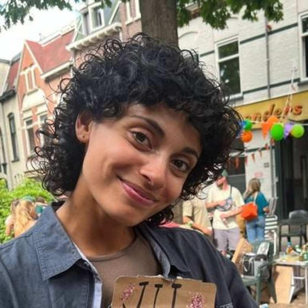 Student Lucy van Haalen, master social work van academie mens en maatschappij. Buiten met donkere krullen en spijkerjasje aan 