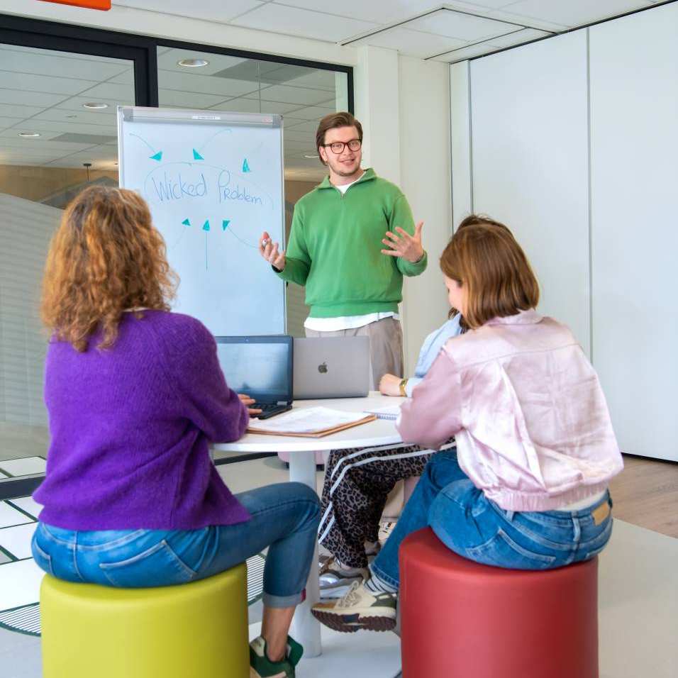 3 masterstudenten aan het werk in een klaslokaal.