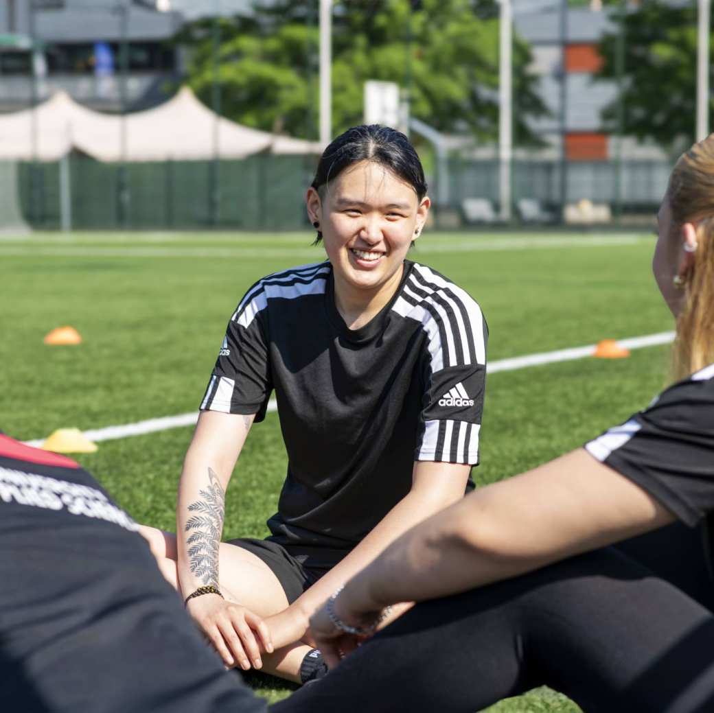 Studenten van de opleiding Sportkunde kletsen met elkaar buiten op het sportveld