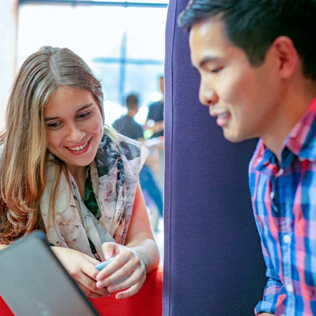 Twee studenten van de HAN overleggen met elkaar terwijl ze op een laptop kijken.