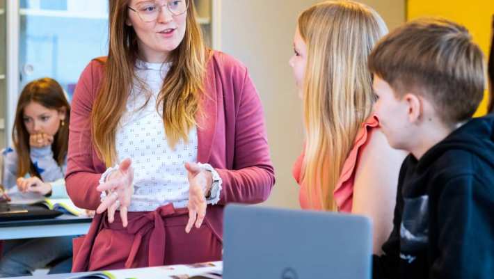 Fotoshoot op het Citadel 2024. De docent gebruikt gebaren om uitleg te geven aan een jongen en een meisje in de klas. 