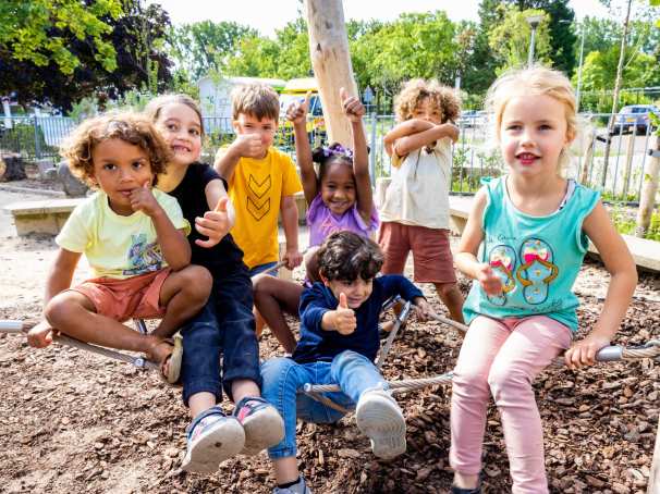 Zeven kinderen poseren buiten op het klimnet. Foto van de opleiding leraar basisonderwijs 