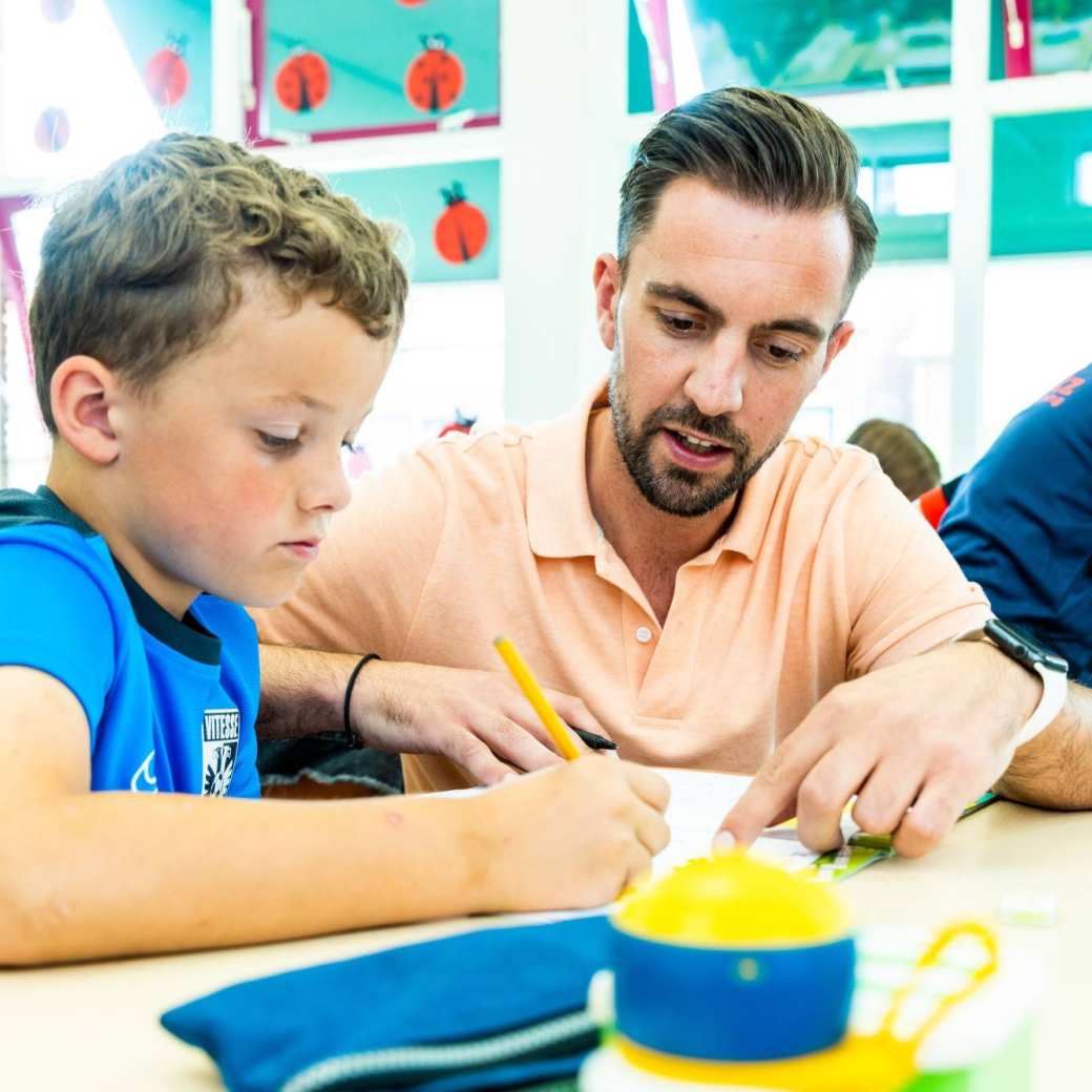 FastSwitcher en meester legt iets uit aan een basisschoollleerling.