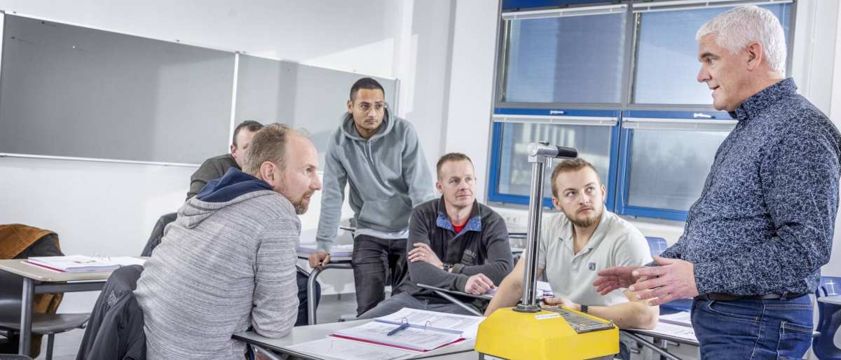 cursisten asfaltwegenbouwlaborant in klas met geel beton apparaat en docent