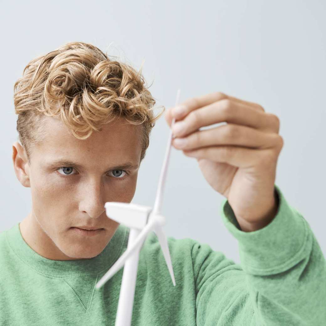 Jongen met een gronee trui bij een model van een windmolen