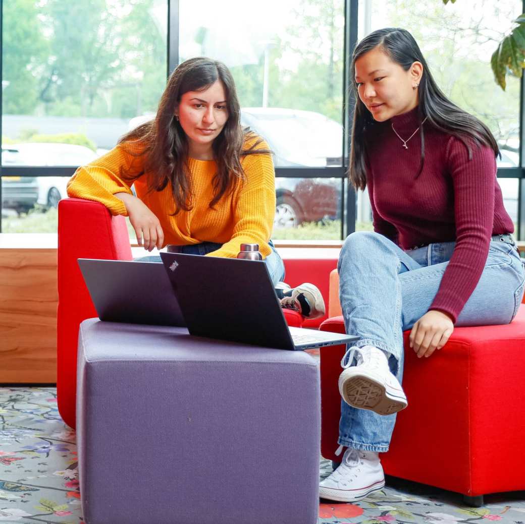 Twee internationael studenten overleggen met laptop bij rode banken