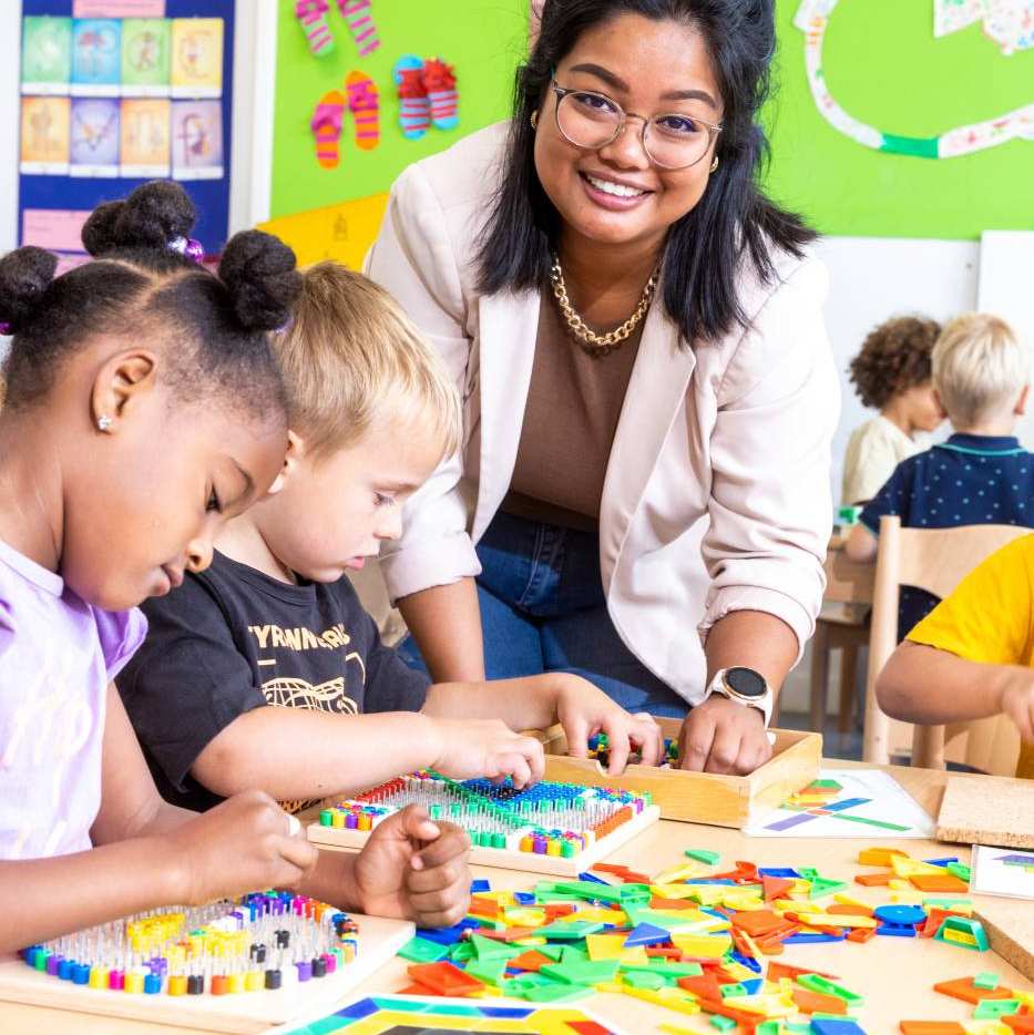 De lerares van de opleiding leraar basisonderwijs helpt de leerlingen bij het leggen van een puzzel