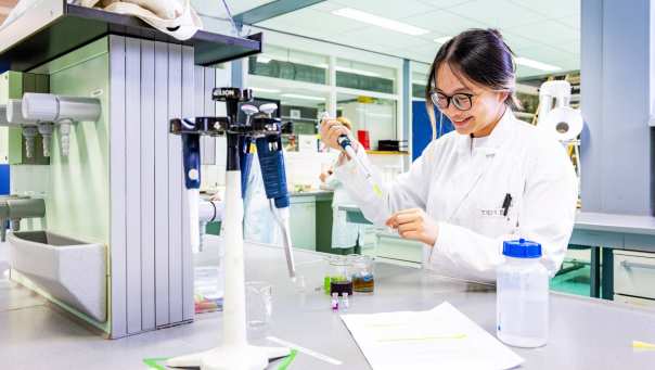 student aan de slag met een pipet in het chemielab