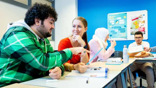 4 NT-2 cursisten overleggen met elkaar tijdens een les.
