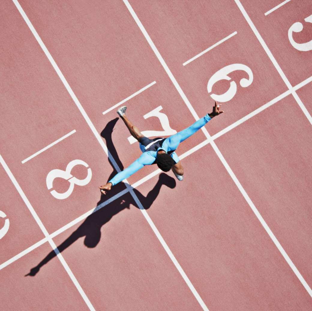 Topsport: een hardloopster rent over de finish van een atletiekbaan