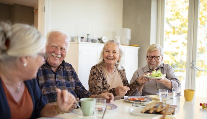 Groep ouderen aan tafel tijdens het ontbijt in een verpleeghuis