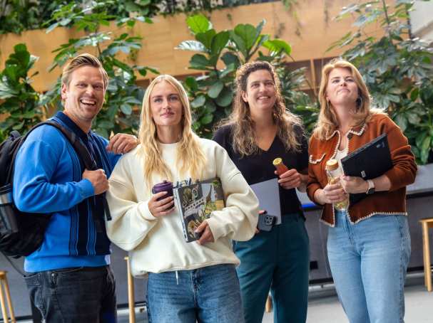 Staande groep studenten lachen en wandelen richting camera