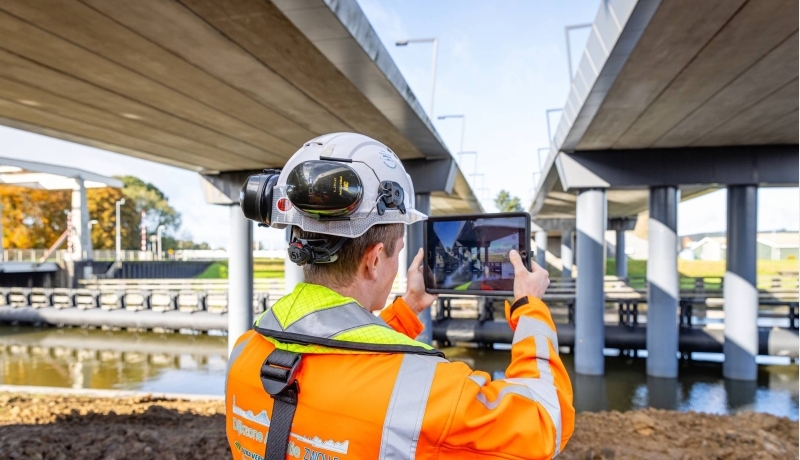 Man met tablet bij een brug