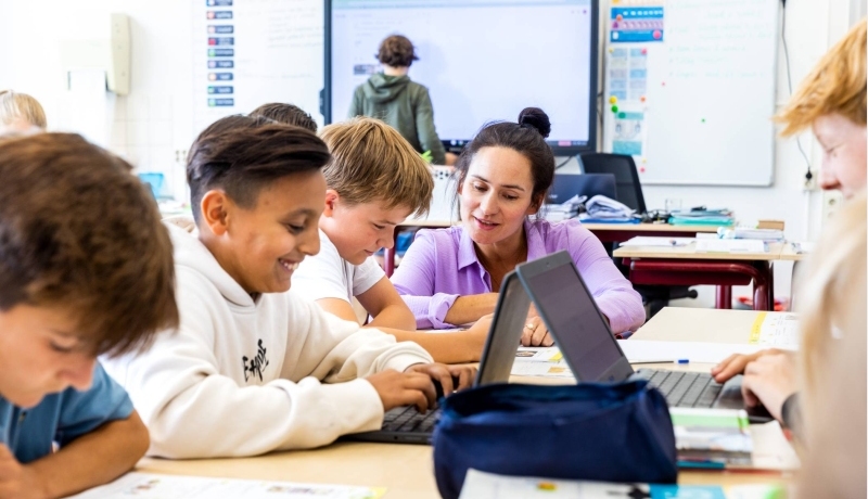 Leraar legt iets uit aan drie jongens in de klas.