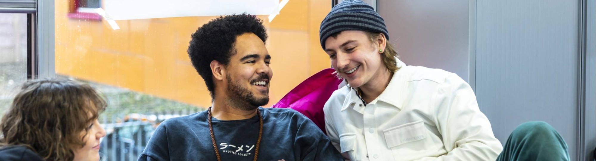 International Social Work. Drie studenten in gesprek. De middelste heeft een laptop. Ze zitten er relaxt bij.