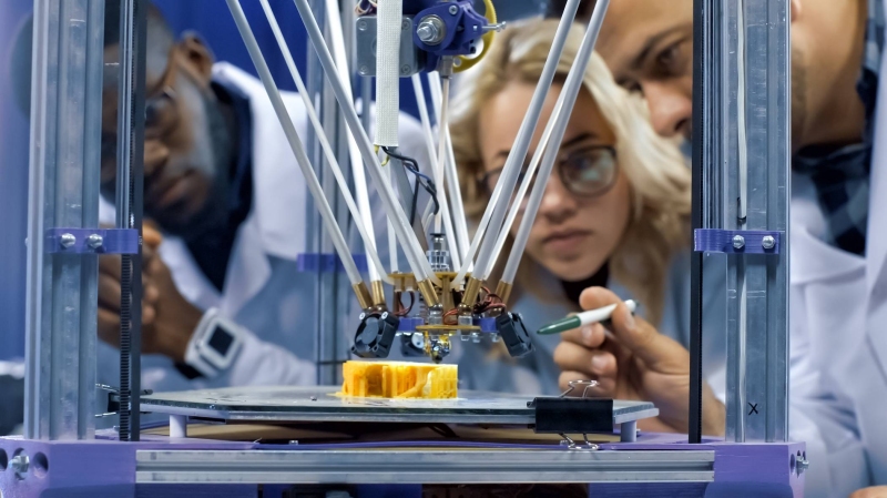 3 mensen bij een 3D printer
