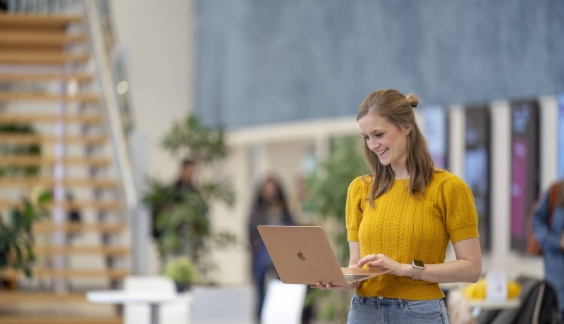 Deeltijdstudent communicatie kijkt op haar laptop op de campus.