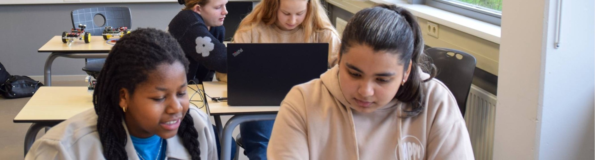 Leerlingen met docent achter laptop