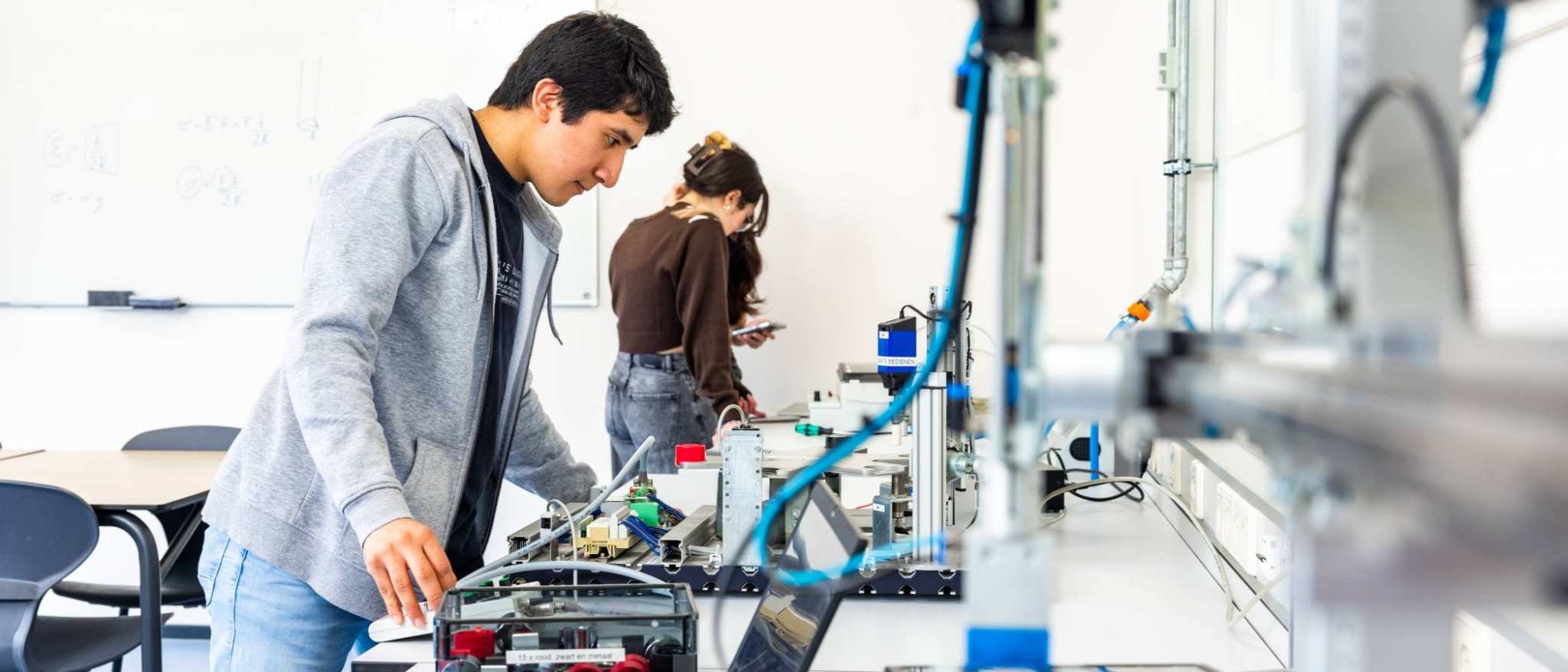 Elektrotechniekstudent Juan werkt aan een PLC in een practicumruimte.