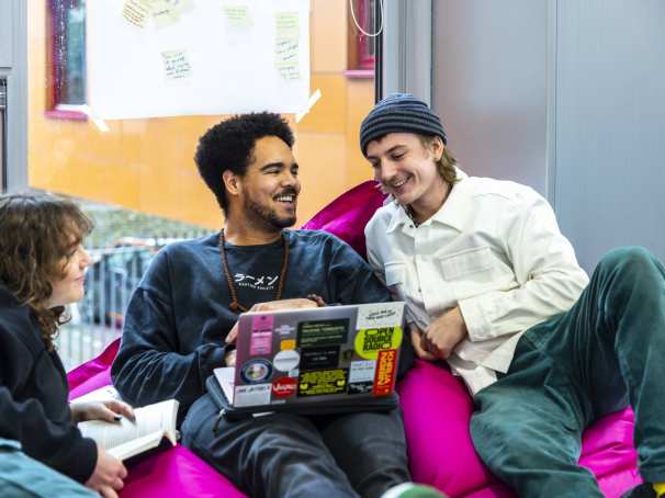 International Social Work. Drie studenten in gesprek. De middelste heeft een laptop. Ze zitten er relaxt bij.