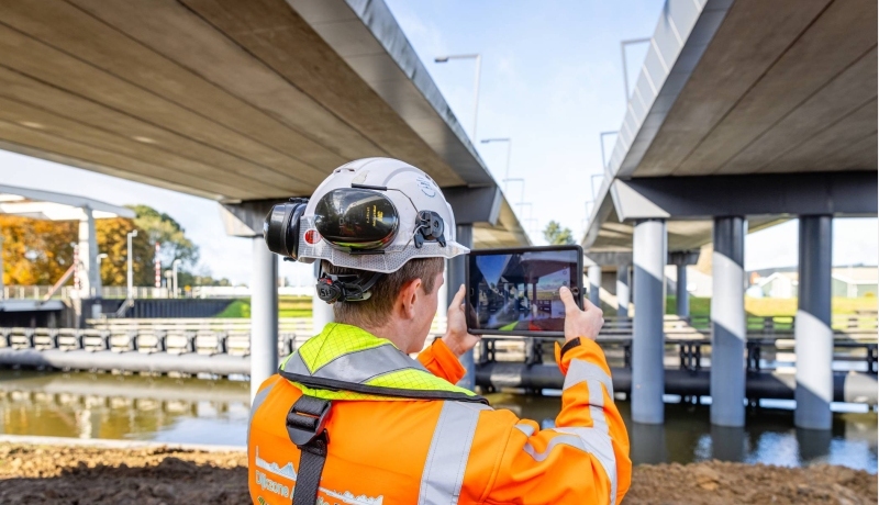 Man met tablet bij een brug