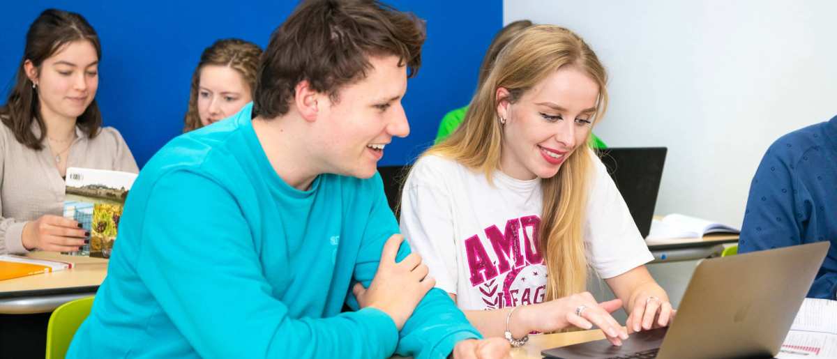 Twee studenten leraar Duits werken samen op één laptop.