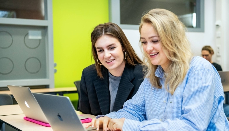 2 studenten Ad POH zitten achter een laptop te overleggen.