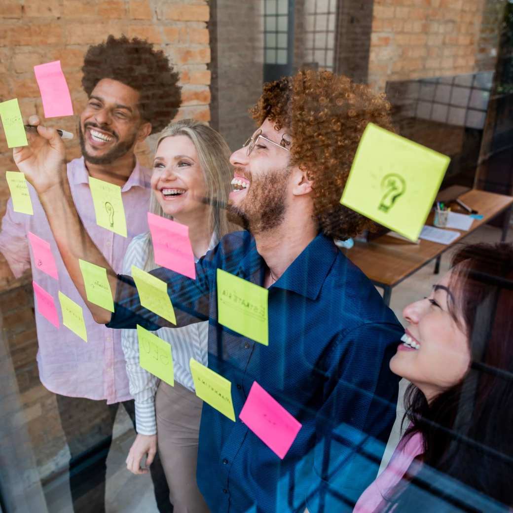 Groep jonge mensen plakken post-its op een glazen wand in een kantoor