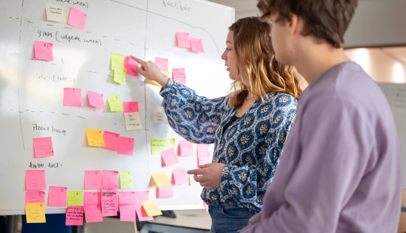 Studenten plakken post-its, projectonderwijs in de klas.