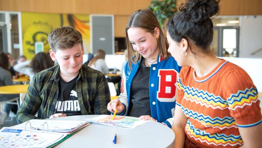 twee studenten in gesprek met docent aan tafel voor de fotoshoot van Leerlab bij Citadel 