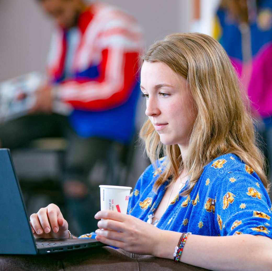Student aan het werk/leren op laptop met koffie