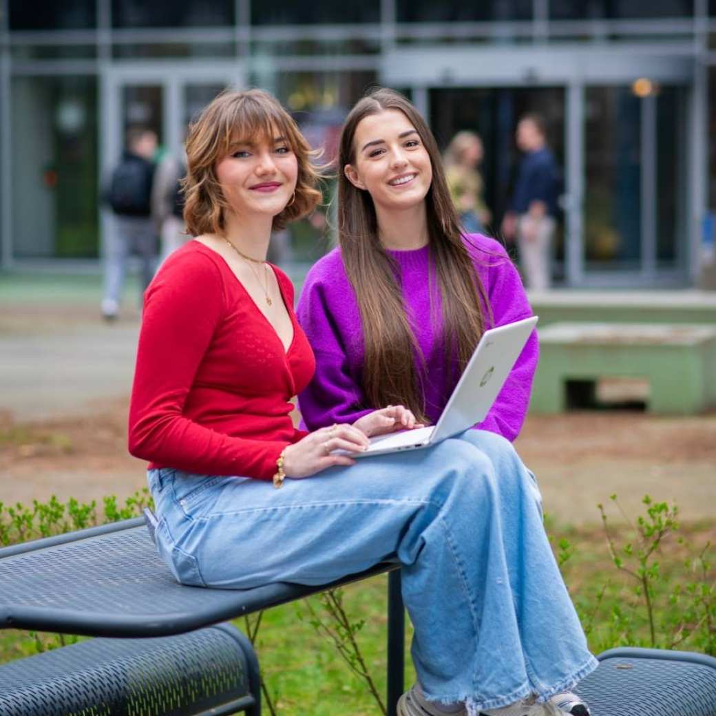 Studenten van Learning and Development in Organisations voltijd kijken lachend in de camera buiten voor Laan van Scheut 10 in Nijmegen.