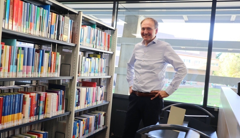 Docent-onderzoeker Ger Sluman staand voor boekenkast in het studiecentrum op Ruitenberglaan 31, na een interview over zijn onderzoek.