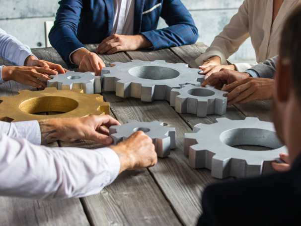 5 mensen aan een houten tafel draaien aan grote radars. Samenwerken. Seece