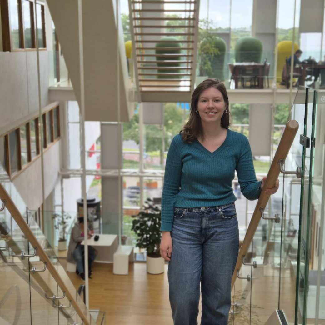 Een vrouw op een trap met een turquoise blouse aan