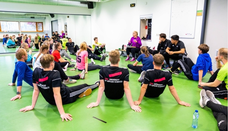 Studenten luisteren in de sportles naar docente.