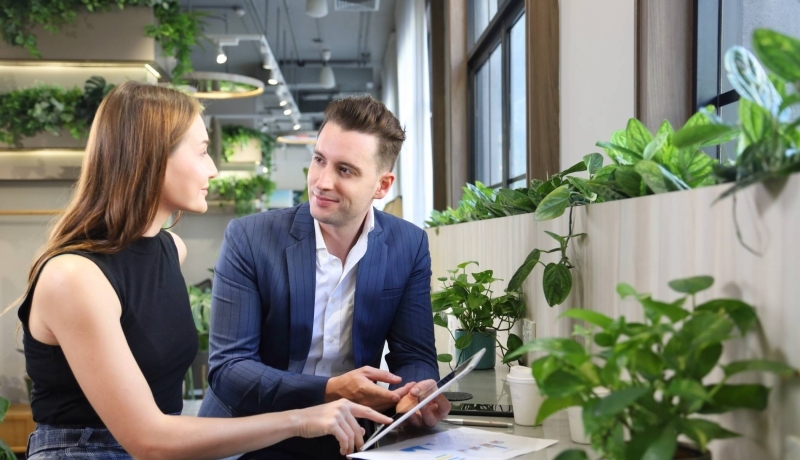 Foto van twee mensen in overleg met een tablet in kantoorruimte met planten voor projectpagina van het ass. lectoraat Sustianable Finance & Tax.