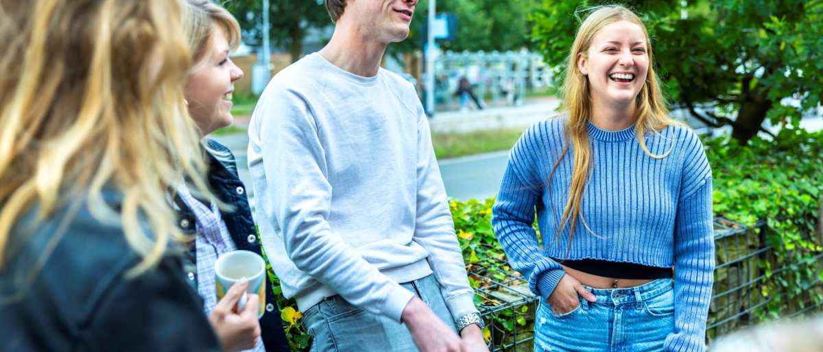 Een groep studenten HAN Social Work zijn samen buiten in gesprek.