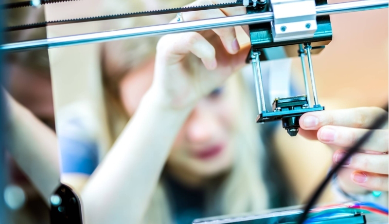Deeltijdstudent bezig met 3D-printer in laboratorium.