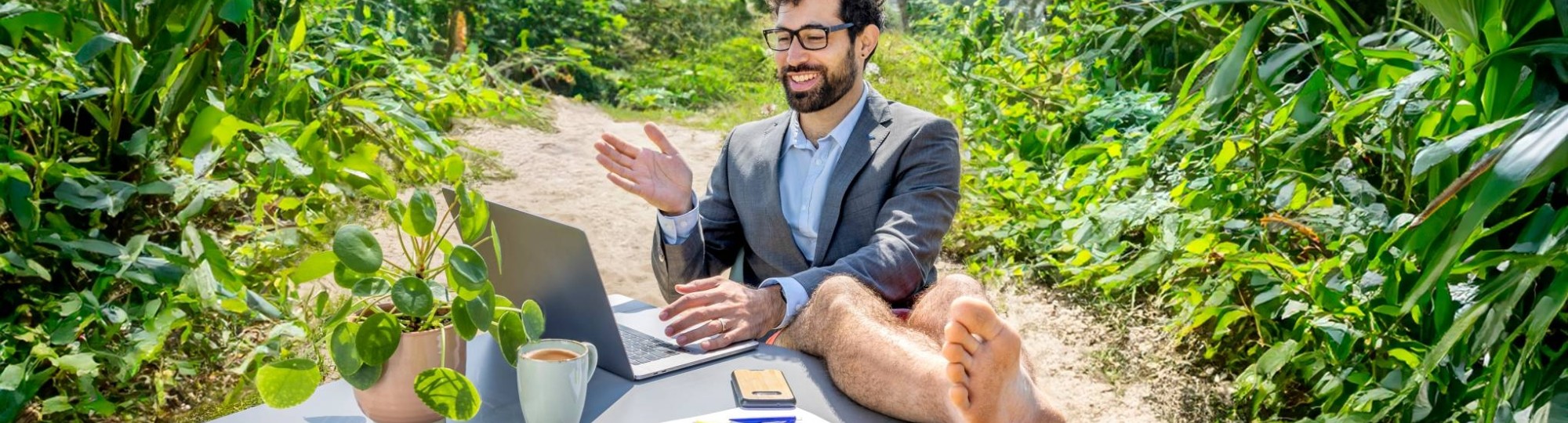 Man zit achter laptop in de jungle met zijn benen omhoog