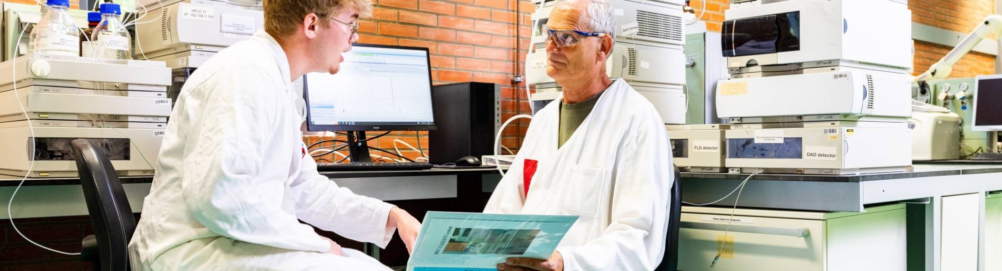 docent geeft uitleg aan student in chemie lab