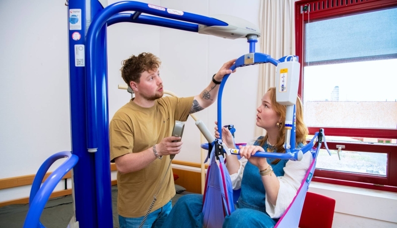 Studenten Ergotherapie lopen buiten bij de HAN campus en kijken elkaar aan.