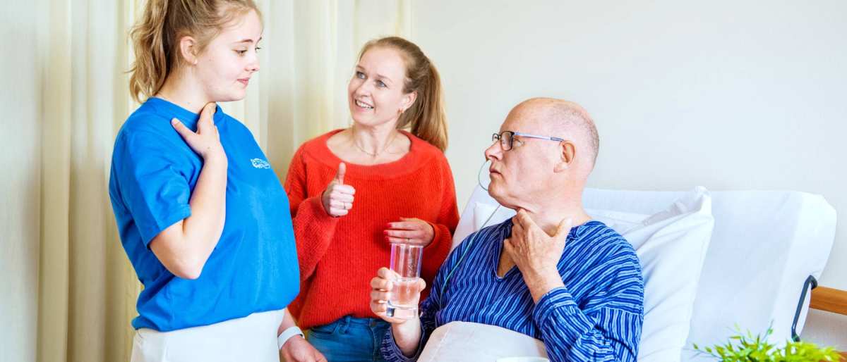 Studenten Logopedie staan bij bed client en geven uitleg