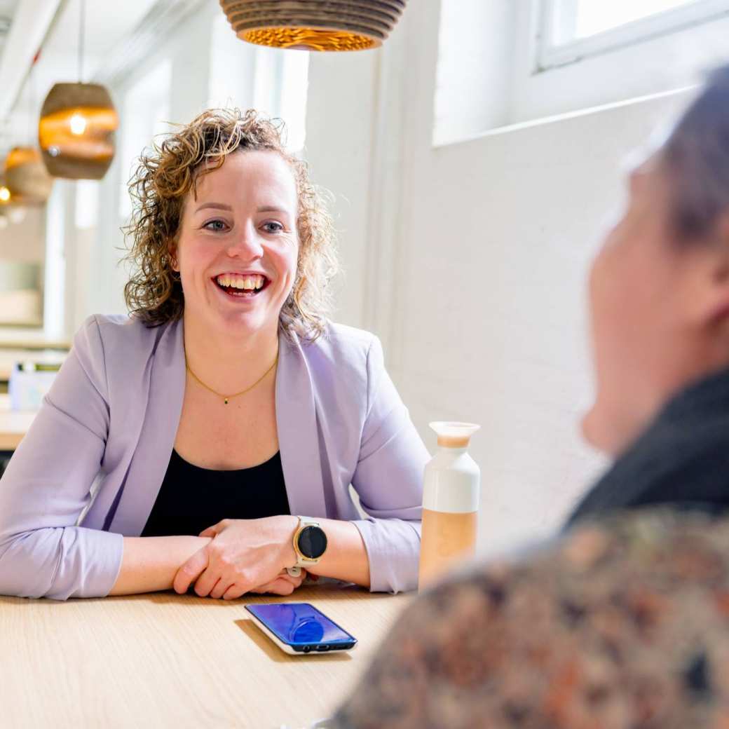 Vrouw in gesprek, moet lachen. Tijdens de cursus acute pijn service, in de kantine.