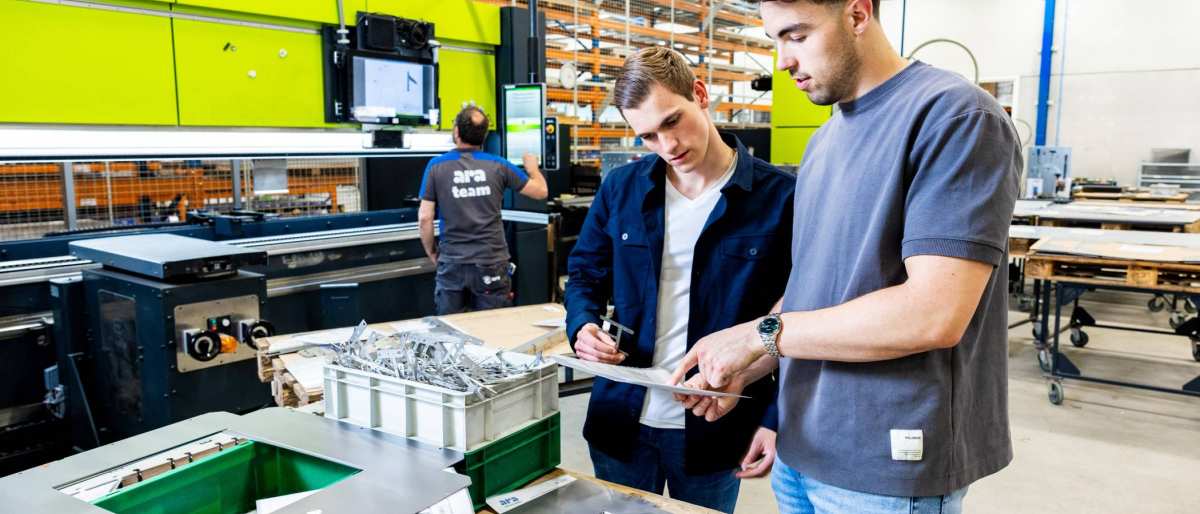 Twee studenten Technische Bedrijfskunde overleggen op de werkvloer van ARA.
