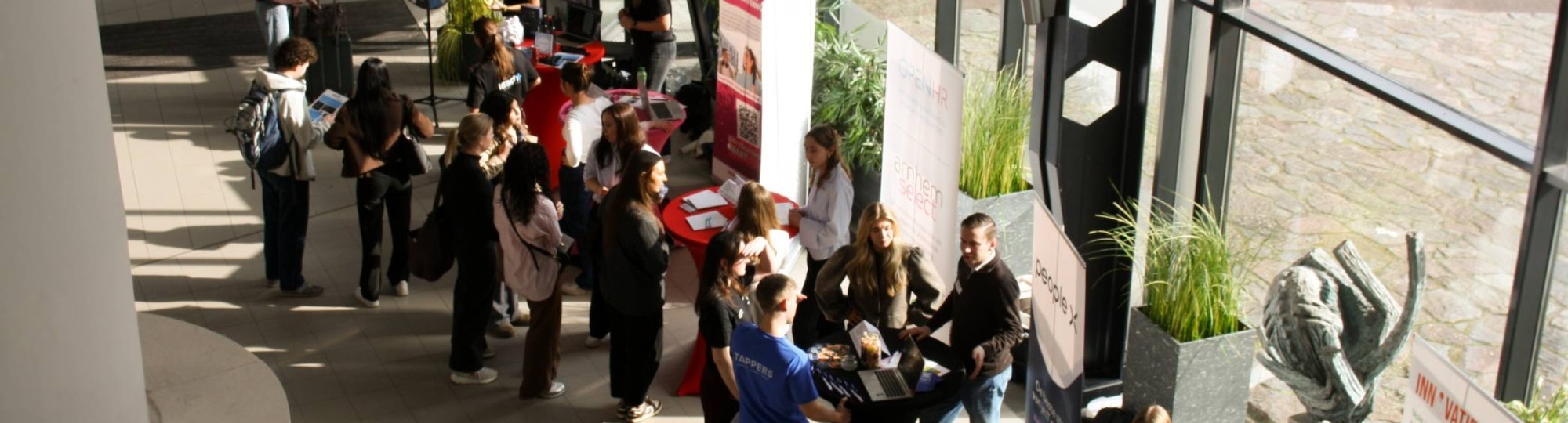 Netwerkmarkt 9 maart 2026, foto van boven genomen. Je ziet meerdere kraampjes met daarachter werkgevers en studenten die op zoek zijn naar een stage.