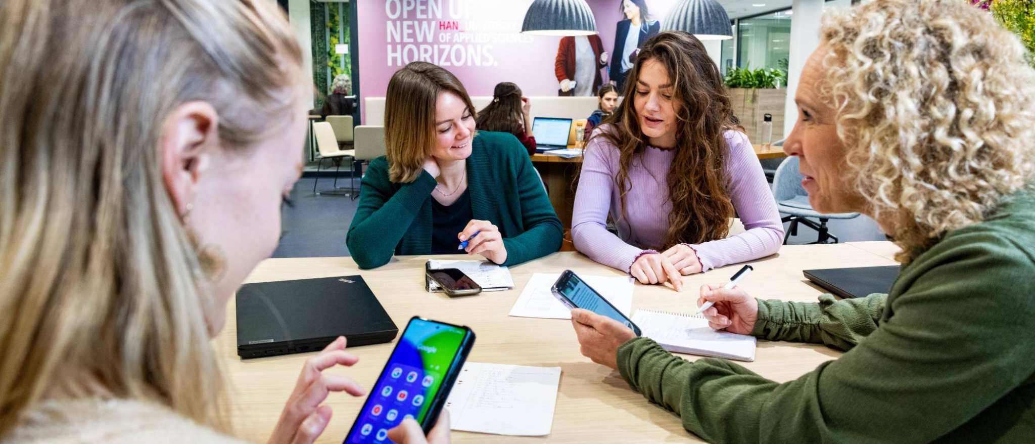Studenten van Logistiek deeltijd zijn in overleg met hun telefoon