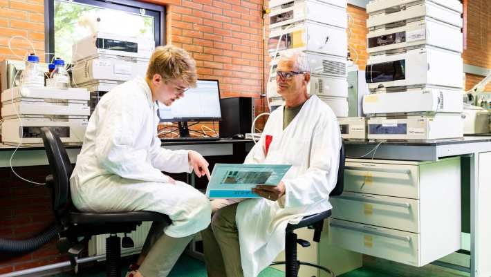 docent geeft uitleg aan student in chemie lab