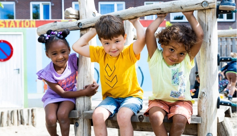 Drie kinderen spelen buiten en hangen aan het klimrek. Foto voor de opleiding leraar basisonderwijs 
