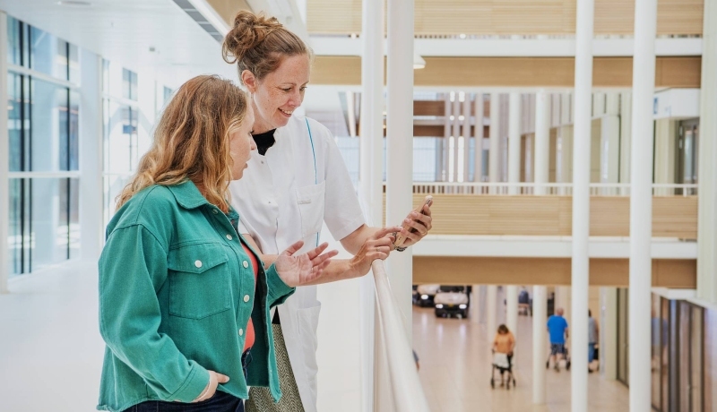 Zorgprofessional laat op telefoon iets zien aan collega